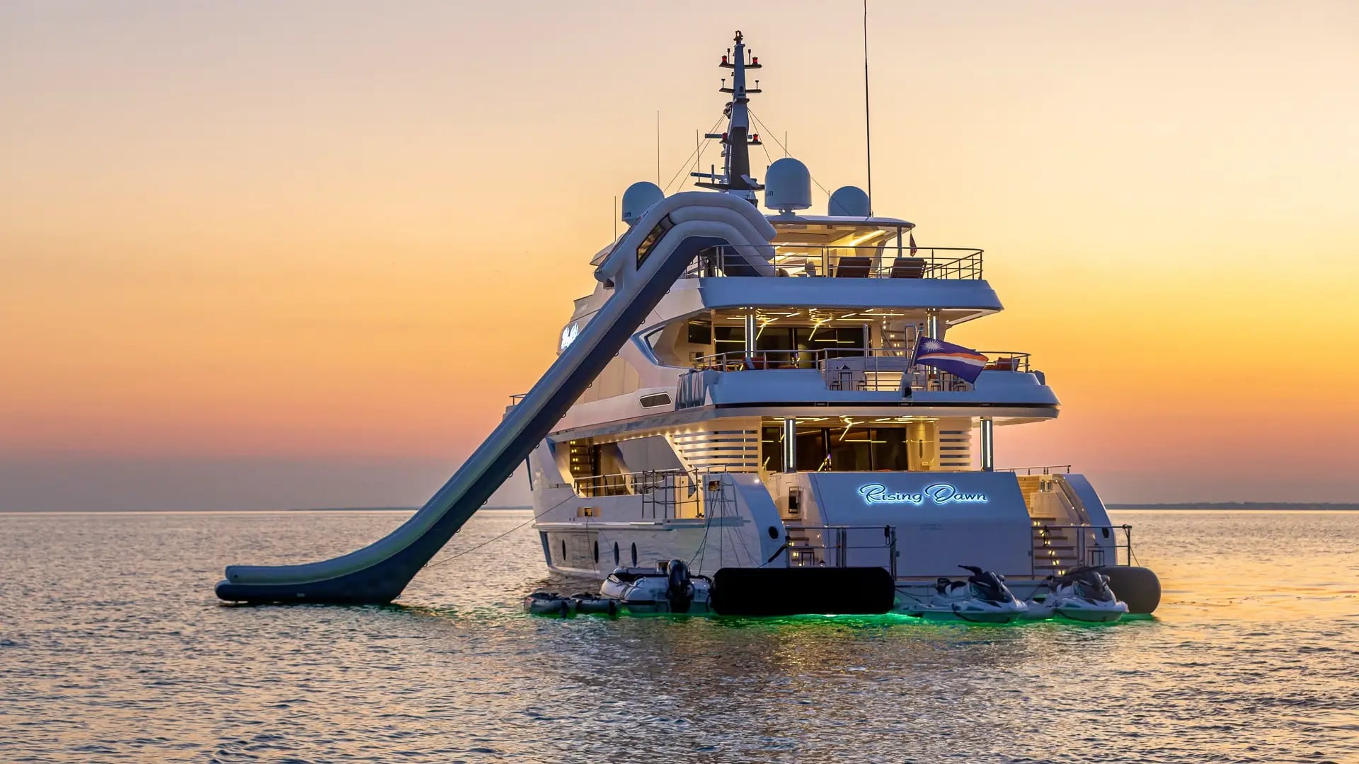 A motor yacht at anchor at sunset with her water slide out